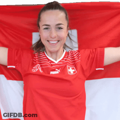 A Woman Wearing A Red Puma Jersey Holds A Swiss Flag GIF