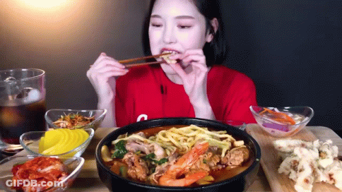 A Woman Wearing A Red Shirt With The Letter C On It Is Eating Noodles With Chopsticks GIF