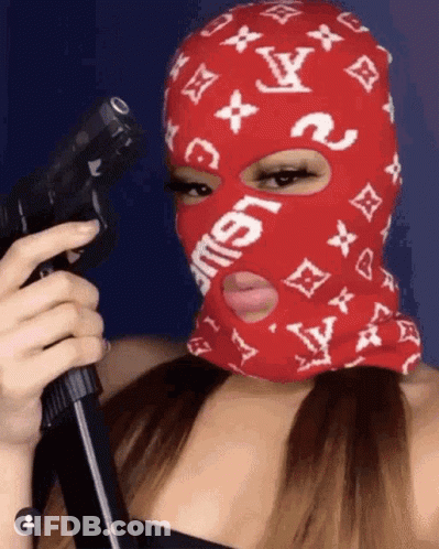 A Woman Wearing A Red Ski Mask Is Holding A Gun GIF