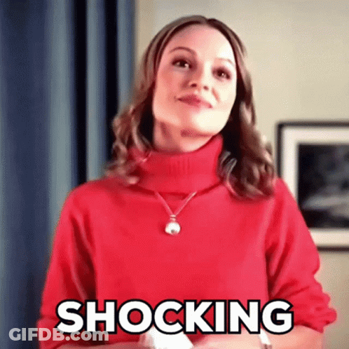 A Woman Wearing A Red Sweater And Necklace Is Making A Shocking Face . GIF