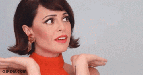 A Woman Wearing A Red Turtleneck And Earrings Is Making A Surprised Face . GIF