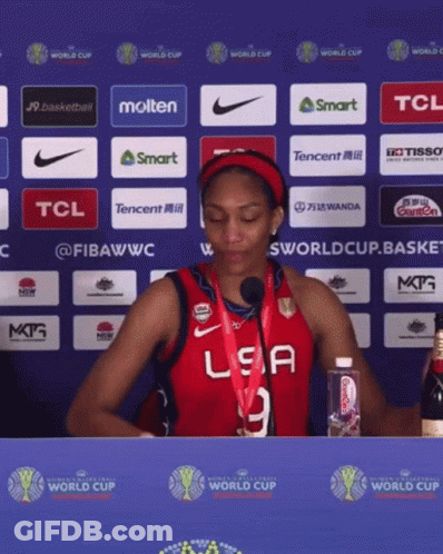 A Woman Wearing A Red USA Jersey Stands In Front Of A Blue Wall GIF