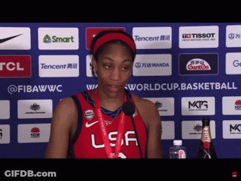A Woman Wearing A Red Usa Jersey Stands In Front Of A Tcl Advertisement GIF