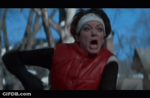 A Woman Wearing A Red Vest And A Headband Is Making A Funny Face . GIF