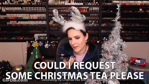 A Woman Wearing A Reindeer Antlers Headband Says Could I Request Some Christmas Tea Please GIF