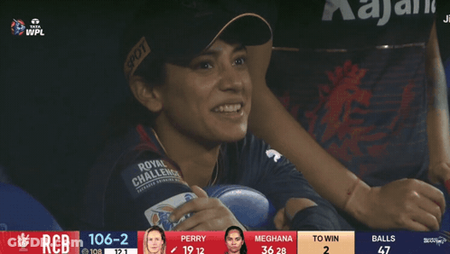 A Woman Wearing A Royal Challenge Jersey Sits In A Stadium GIF