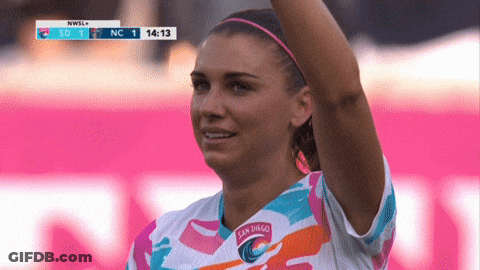 A Woman Wearing A San Diego Soccer Jersey Stands In Front Of A Scoreboard GIF