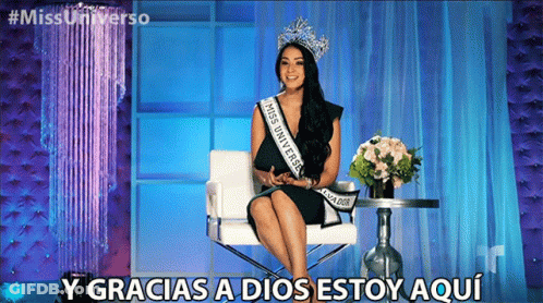A Woman Wearing A Sash That Says Miss Universe Is Sitting In A Chair GIF