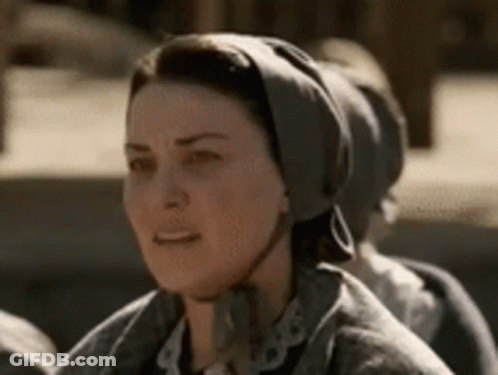 A Woman Wearing A Scarf Around Her Head Is Sitting In A Row Of People . GIF