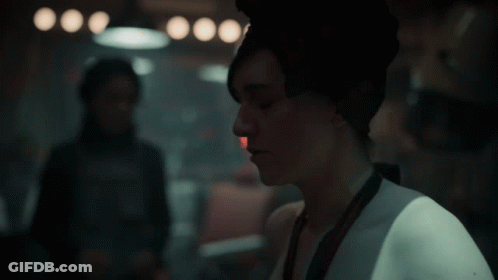 A Woman Wearing A Scarf Around Her Head Looks To The Side GIF