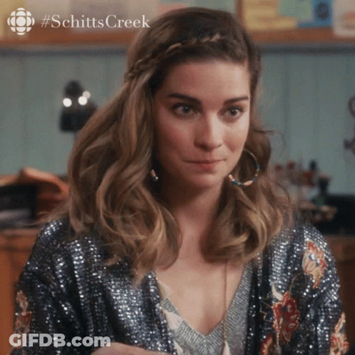 A Woman Wearing A Sequined Jacket And Hoop Earrings With #Schittscreek Written On The Bottom GIF