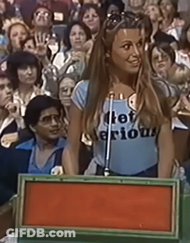 A Woman Wearing A Shirt That Says " Let 'S Be Serious " Stands In Front Of A Microphone GIF
