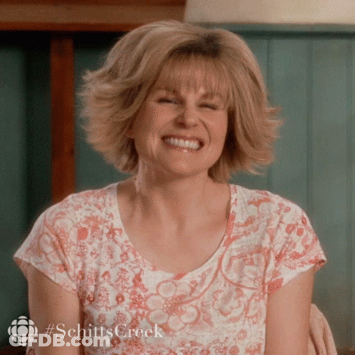 A Woman Wearing A Shirt That Says Schitts Creek Smiles GIF