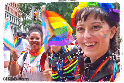 A Woman Wearing A Shirt That Says " Shine " Smiles While Holding A Rainbow Flag GIF