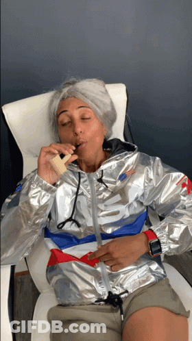 A Woman Wearing A Silver Nike Jacket Is Smoking An Electronic Cigarette GIF