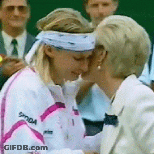 A Woman Wearing A Skoda Jacket Is Kissing Another Woman On The Cheek GIF