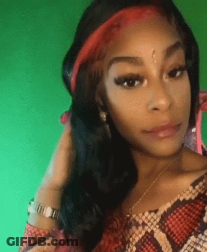A Woman Wearing A Snake Print Shirt And A Red Headband Is Looking At The Camera . GIF