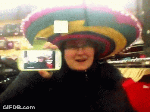 A Woman Wearing A Sombrero Is Taking A Picture Of Herself With A Cell Phone GIF