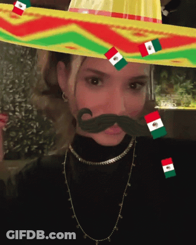 A Woman Wearing A Sombrero With Flags On It GIF