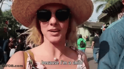 A Woman Wearing A Straw Hat And Sunglasses Is Standing In A Crowded Area . GIF
