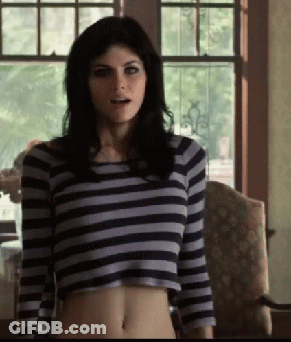 A Woman Wearing A Striped Crop Top Stands In Front Of A Window GIF