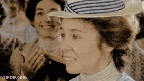 A Woman Wearing A Striped Hat Is Smiling In Front Of Two Other Women GIF