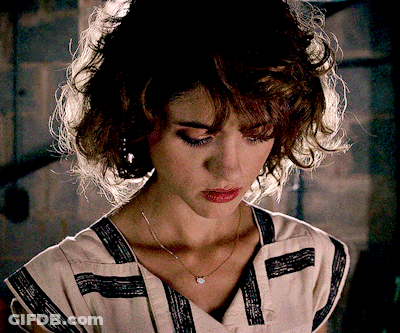 A Woman Wearing A Striped Shirt And A Necklace Looks Down At Something GIF