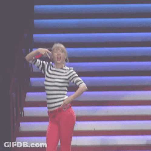 A Woman Wearing A Striped Shirt And Red Pants Is Dancing On A Stage GIF