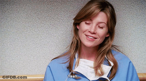 A Woman Wearing A Surgical Mask And A Blue Scrub Is Smiling And Talking . GIF