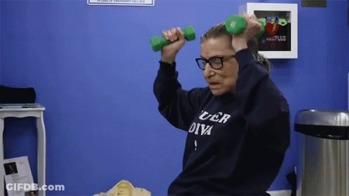 A Woman Wearing A Sweater That Says Uber Diva Is Lifting Dumbbells GIF