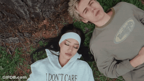 A Woman Wearing A Sweatshirt That Says I Do N't Care Lays Next To A Man GIF