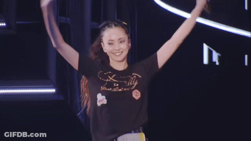 A Woman Wearing A T-Shirt That Says Finally Is Standing On Stage GIF