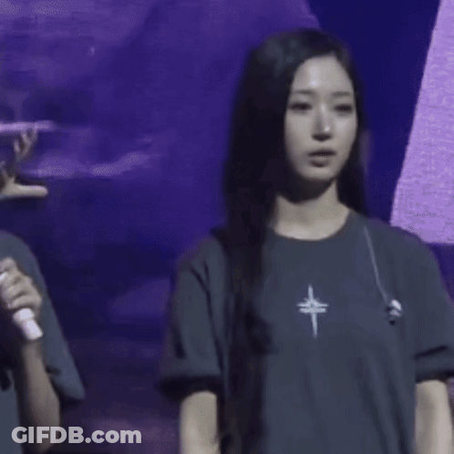 A Woman Wearing A T-Shirt With A Cross On It Is Waving Her Hand GIF