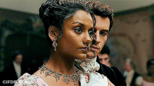 A Woman Wearing A Tiara Is Standing Next To A Man In A Tuxedo GIF