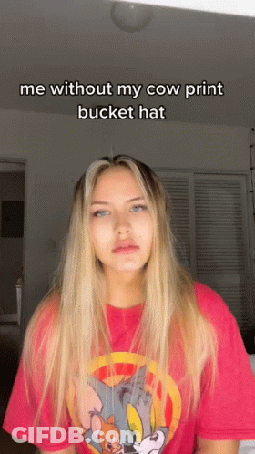 A Woman Wearing A Tom And Jerry Shirt Says " Me Without My Cow Print Bucket Hat " On The Bottom GIF