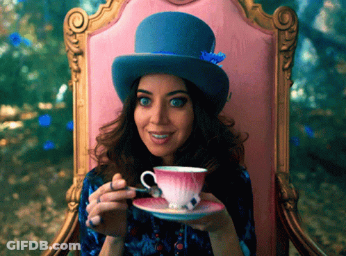 A Woman Wearing A Top Hat Is Sitting In A Chair Drinking From A Teacup GIF