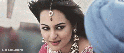 A Woman Wearing A Turban And Earrings Is Looking At A Man . GIF
