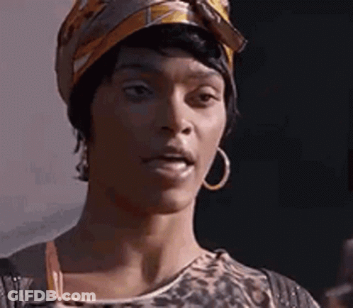 A Woman Wearing A Turban And Hoop Earrings Is Making A Funny Face . GIF