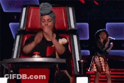 A Woman Wearing A Turban Is Sitting In A Chair On A Stage With A Microphone . GIF