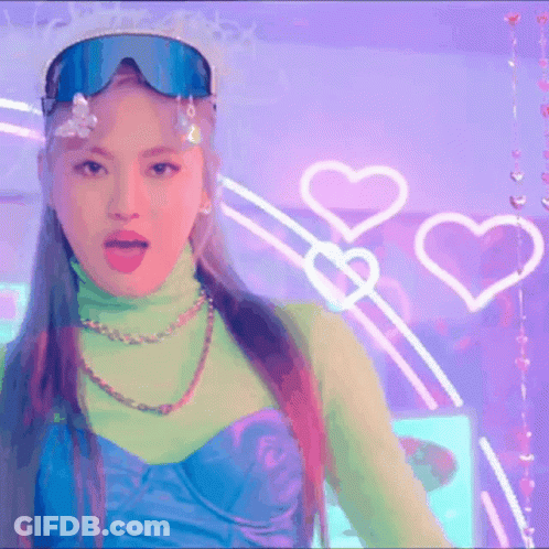 A Woman Wearing A Turtleneck And Goggles Is Standing In Front Of A Purple Wall With Hearts . GIF