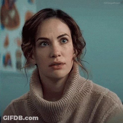 A Woman Wearing A Turtleneck Sweater Is Looking At The Camera . GIF