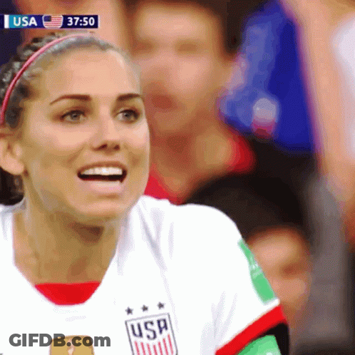 A Woman Wearing A Usa Jersey Smiles While Watching A Soccer Game GIF