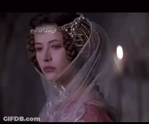 A Woman Wearing A Veil And A Crown Looks At The Camera GIF