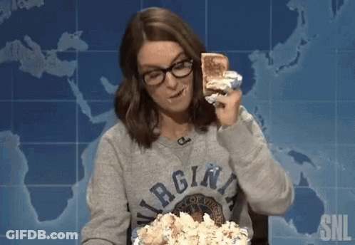 A Woman Wearing A Virgina Sweatshirt Is Eating A Sandwich And Popcorn GIF