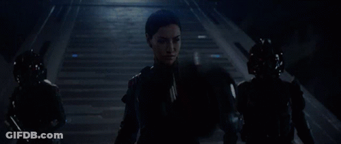 A Woman Wearing A Virtual Reality Headset Stands In A Dark Room GIF