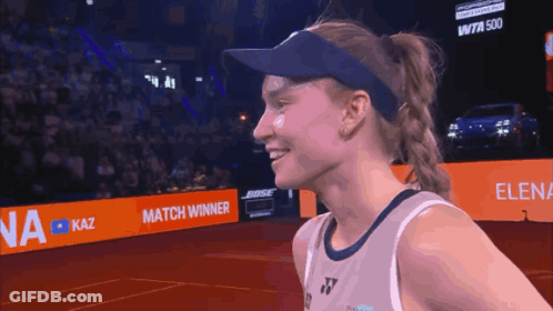 A Woman Wearing A Visor Stands In Front Of A Bose Ad GIF