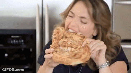 A Woman Wearing A Watch Is Eating A Piece Of Bread GIF
