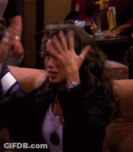 A Woman Wearing A Watch Is Sitting On A Couch Covering Her Face With Her Hand GIF