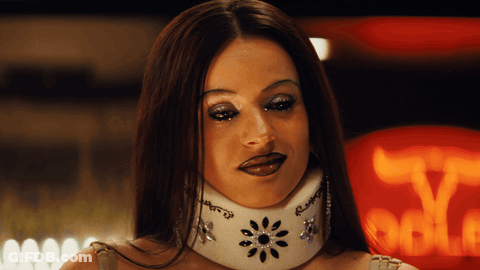 A Woman Wearing A White Collar With Rhinestones On It Looks At The Camera GIF