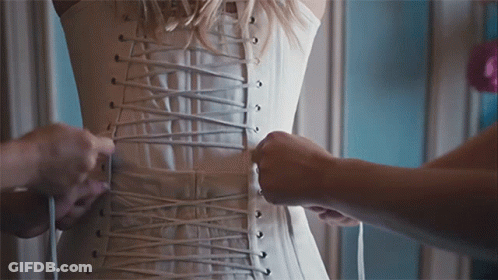 A Woman Wearing A White Corset Is Being Laced Up GIF